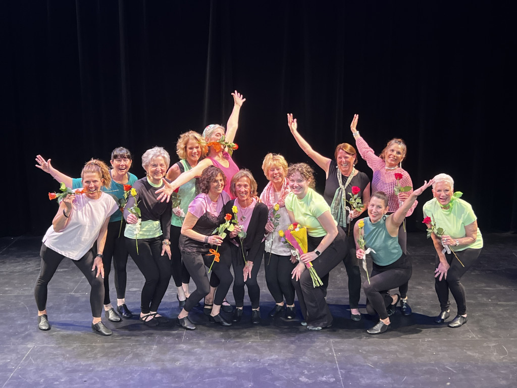 group of adult dancers wearing pink and green shirts and holding roses silly posing